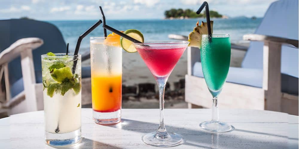four cocktails on a white table overlooking the beach