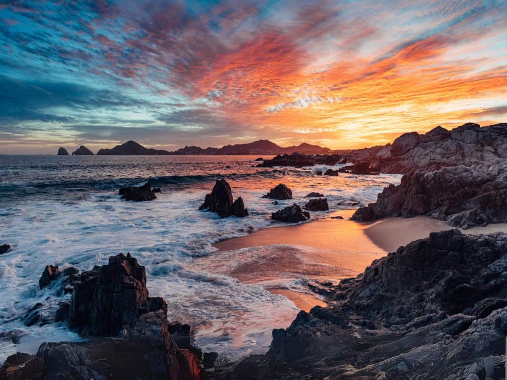dramatic sunset in Cabo San Lucas with a view of Lands End at the horizon